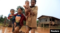 Parents carry their children as they leave their home during the flood after the Xepian-Xe Nam Noy hydropower dam collapsed in Attapeu province, Laos