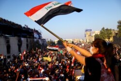 An Iraqi female demonstrator waves an Iraqi flag during an ongoing anti-government protest, in Baghdad, Iraq, Nov. 1, 2019.