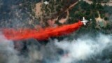 An aircraft lays down a line of fire retardant between a wildfire and homes in the dry, densely wooded Black Forest area northeast of Colorado Springs, Colorado, June 13, 2013.