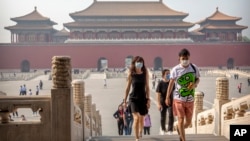 Para pengunjung mengenakan masker untuk melindungi dari penularan virus corona di Kota Terlarang, Beijing, 1 Mei 2020. (Foto: AP) 