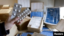 FILE: A Swiss customs officer holds up counterfeit medication in Bardonnex, near Geneva, February 10, 2010. Central African Republic officials say unlicensed pharmacies - "doctas - may be the source of counterfeit and potentially dangerous drugs. 