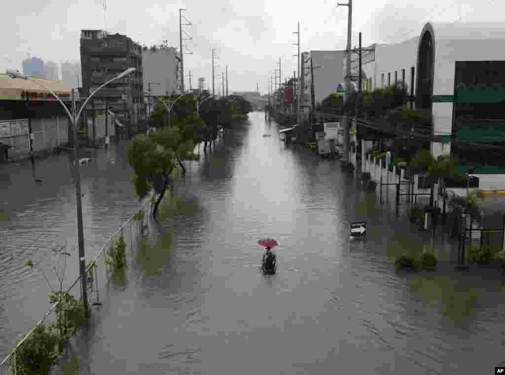 Warga menggunakan perahu kecil untuk transportasi di jalan yang terkena banjir akibat Topan Usagi di pinggir kota Quezon city, timur laut Manila (23/9). (AP/Bullit Marquez)