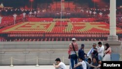 Para pengunjung beristirahat di depan layar lebar yang menayangkan video propaganda di Lapangan Tiananmen di Beijing (31/5). Kelompok aktivis "Para Ibu Tiananmen" menuntut agar para pemimpin China memulai dialog dan menilai kembali penindakan di Lapangan Tiananmen di Beijing tanggal 4 Juni 1989, yang menewaskan hampir tiga ribu pemrotes.