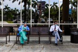 Seorang dokter (L) yang mengenakan peralatan pelindung diri menggunakan telepon genggamnya ketika ia duduk di luar Rumah Sakit Jackson Memorial di Miami, pada 13 Juli 2020. (Foto: AFP)