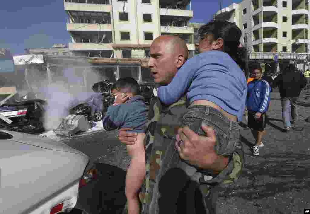 A Lebanese army soldier carries two injured children away from the site of an explosion near the Kuwaiti Embassy and Iran&#39;s cultural center, in the suburb of Beir Hassan, Beirut, Lebanon, Feb. 19, 2014. 