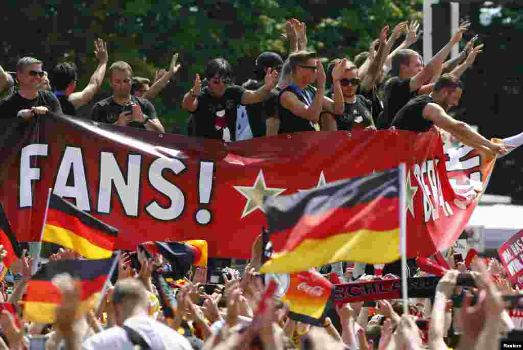 Kepala pelatih Jerman, Joachim Loew (tengah) dan anggota tim Piala Dunia Brazil 2014 Jerman melambaikan tangan pada para penggemar ketika merayakan kemenangan tim mereka di tempat nobar Fan Mile di Berlin, 15 Juli 2014.