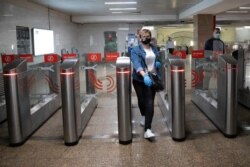 A woman wearing face mask and gloves to protect against coronavirus, observes social distancing guidelines as she passes through the turnstiles of the subway in Moscow, Russia, Tuesday, May 12, 2020.