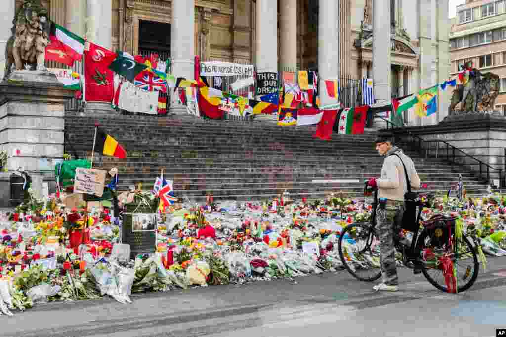 A man looks at a memorial site for the victims of the Brussels attacks at the Place de la Bourse in Brussels, Belgium. The city archive started collecting messages and drawings Friday to protect and preserve them.