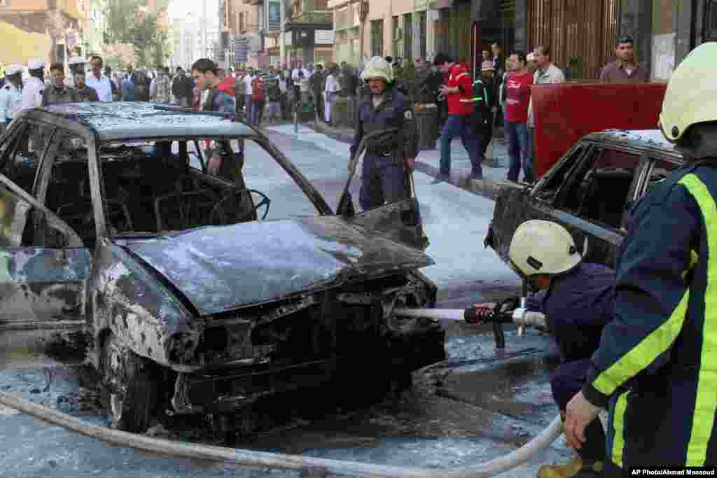 Firefighters extinguish a burning vehicle after two mortar rounds struck the Abu Roumaneh area in Damascus, Syria, Oct. 12, 2013. 