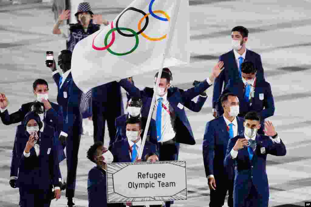 Yusra Mardini and Tachlowini Gabriyesos of the Refugee Olympic Team carry the Olympic flag during the opening ceremony in the Olympic Stadium at the 2020 Summer Olympics, July 23, 2021.