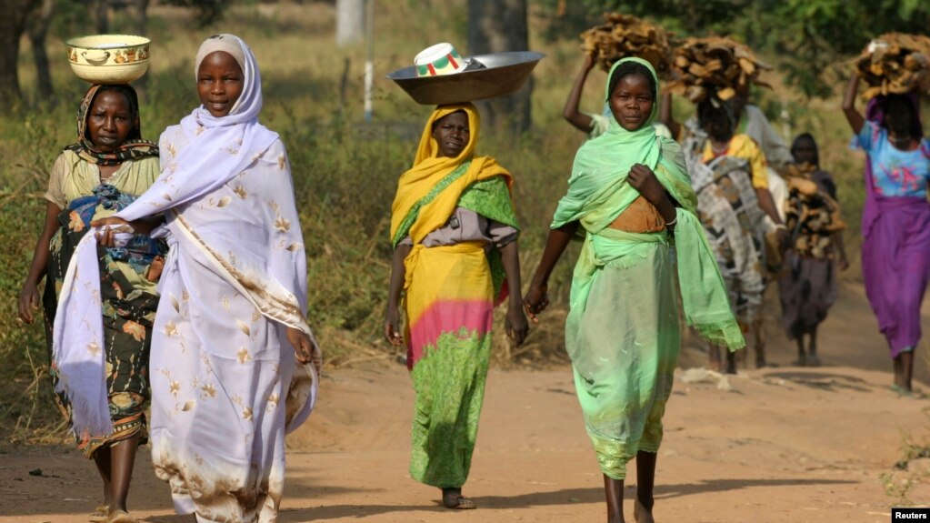 FILE - Sudanese refugees from Darfur carry goods and firewood near the village of Sam Ouandja, in the remote northeast of the Central African Republic, Dec. 6, 2007. Some 1,500 refugees from Darfur in the CAR are scheduled to return home by the end of the year.