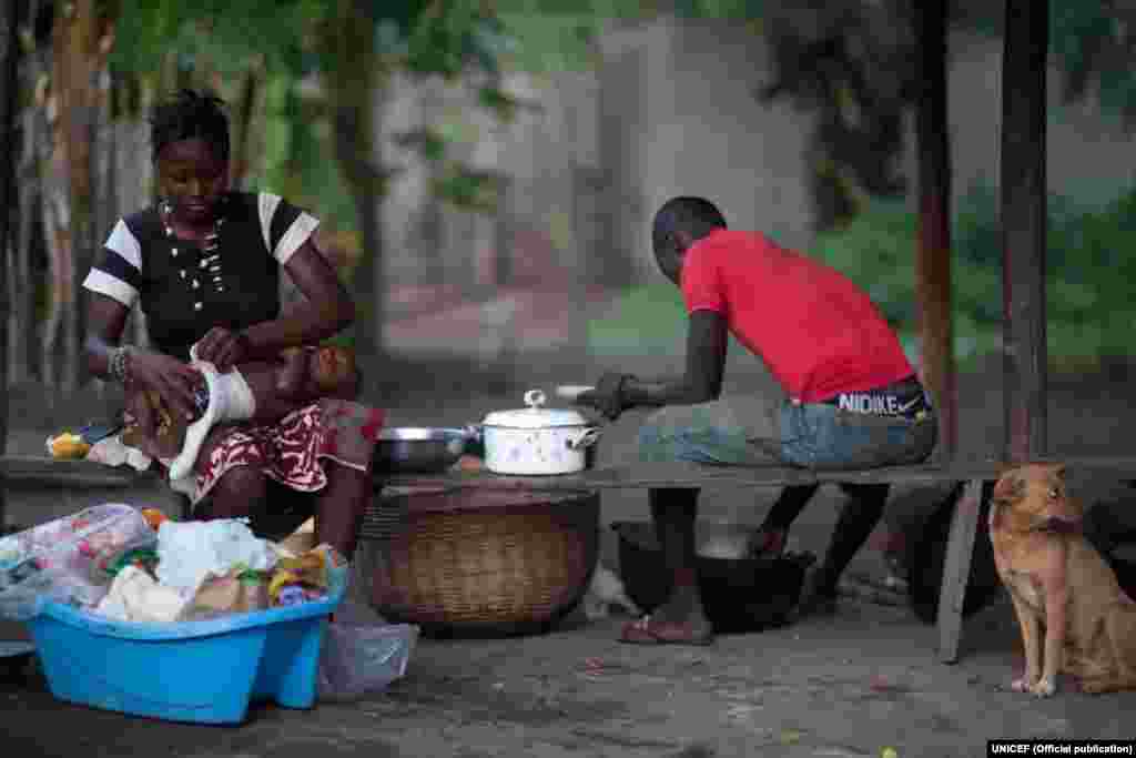 Foto tirada a 14 Nov 2015, Amina Kamara (esq), na altura com 15 anos, trata do filho, Ali, 6 meses na altura, ao lado do marido, Lamine, na vila de Motonko no distrito de Moyamba, Serra Leoa