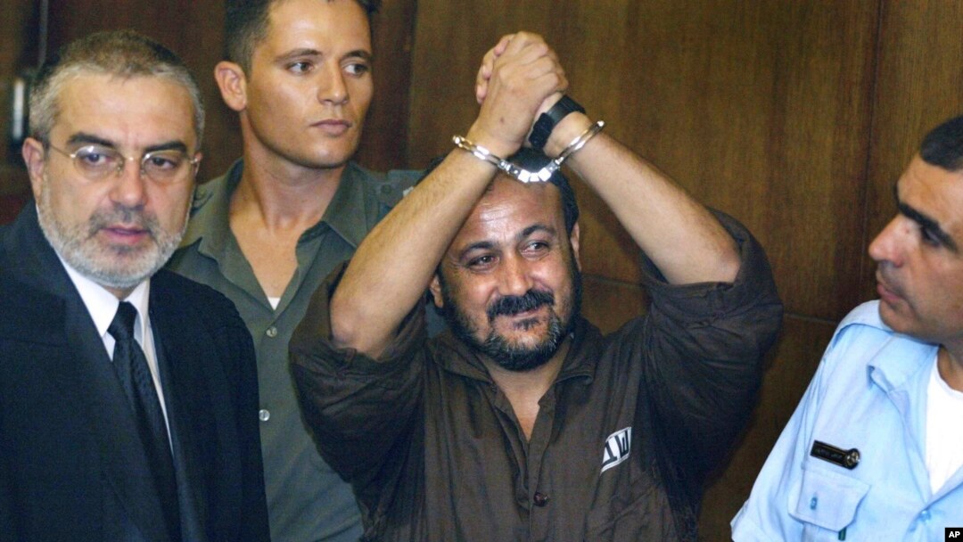  مروان برغوتی، 14 اگست 2002 کو تل ابیب کی ایک عدالت میں اپنے مقدمے کی سماعت کے پہلے دن اپنے ہتھکڑی والے ہاتھ ہوا میں اٹھا رہے ہیں۔ (اے پی فوٹو)
