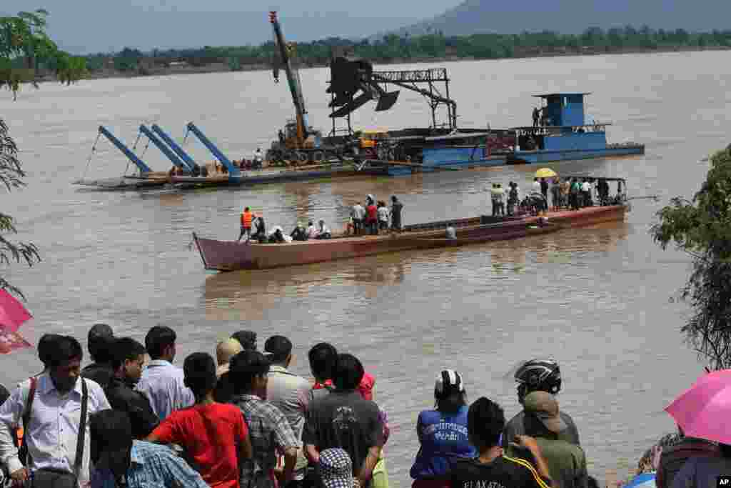 Onlookers watch the search operation for the lost Lao Airlines plane on the banks of the Mekong River in Pakse, Laos, Oct. 17, 2013.