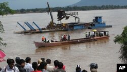 FILE - Onlookers watch the search operation for the lost Lao Airlines plane on the banks of the Mekong River in Pakse, Laos, Oct. 17, 2013.