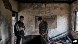 Kashmiri Muslim student Hilal Ahmed Hajam, left, and Nasir Ahmed Mir inspects the damage of a partially burned government high school in Goripora, outskirts of Srinagar, India controlled Kashmir, Nov. 1, 2016. At least 25 schools have been torched in the past three months, amid widespread unrest. 