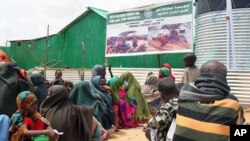 Somalis queue outside a temporary feeding center run by an Islamic charitable group at a Mogadishu IDP camp