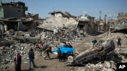 Residents of western Mosul, Iraq, carry the bodies of several people killed during fighting between Iraq security forces and Islamic State, March 24, 2017.