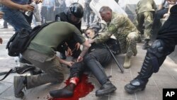 Police officers give a medical aid after grenade blast during a clash between protesters and police after a vote to give greater powers to the east, outside the Parliament, Kiev, Ukraine, Monday, Aug. 31, 2015. 