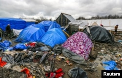 FILE - Migrants walk among tents in a muddy field at a camp of makeshift shelters for migrants and asylum-seekers from Iraq, Kurdistan, Iran and Syria, called the Grande Synthe jungle, near Calais, France, Feb. 3, 2016.