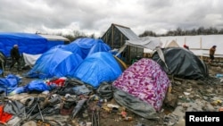 FILE - Migrants walk among tents in a muddy field at the Jungle near Calais, France, Feb. 3, 2016. 