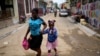 FILE - A child sips on a refreshment as she is walked home from school, in Cap-Haitien, Haiti, April 17, 2024. 