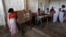 A woman (L) casts her vote with an electronic voting machine as others get their voting slip from an officer at a polling station in Majuli, a large river island in the Brahmaputra river, Jorhat district, in the northeastern Indian state of Assam, April 7