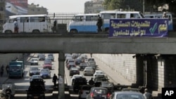 Egyptians drive past a banner calling for a "yes" vote in a referendum on constitutional changes scheduled for Saturday, Cairo, March 17, 2011