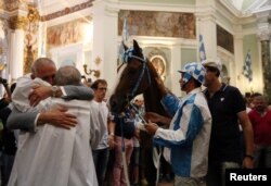 The captain of the Onda parish, Alessandro Toscano, embraces the priest at the church before the Palio di Siena horse race in Siena, Italy, July 2, 2017.