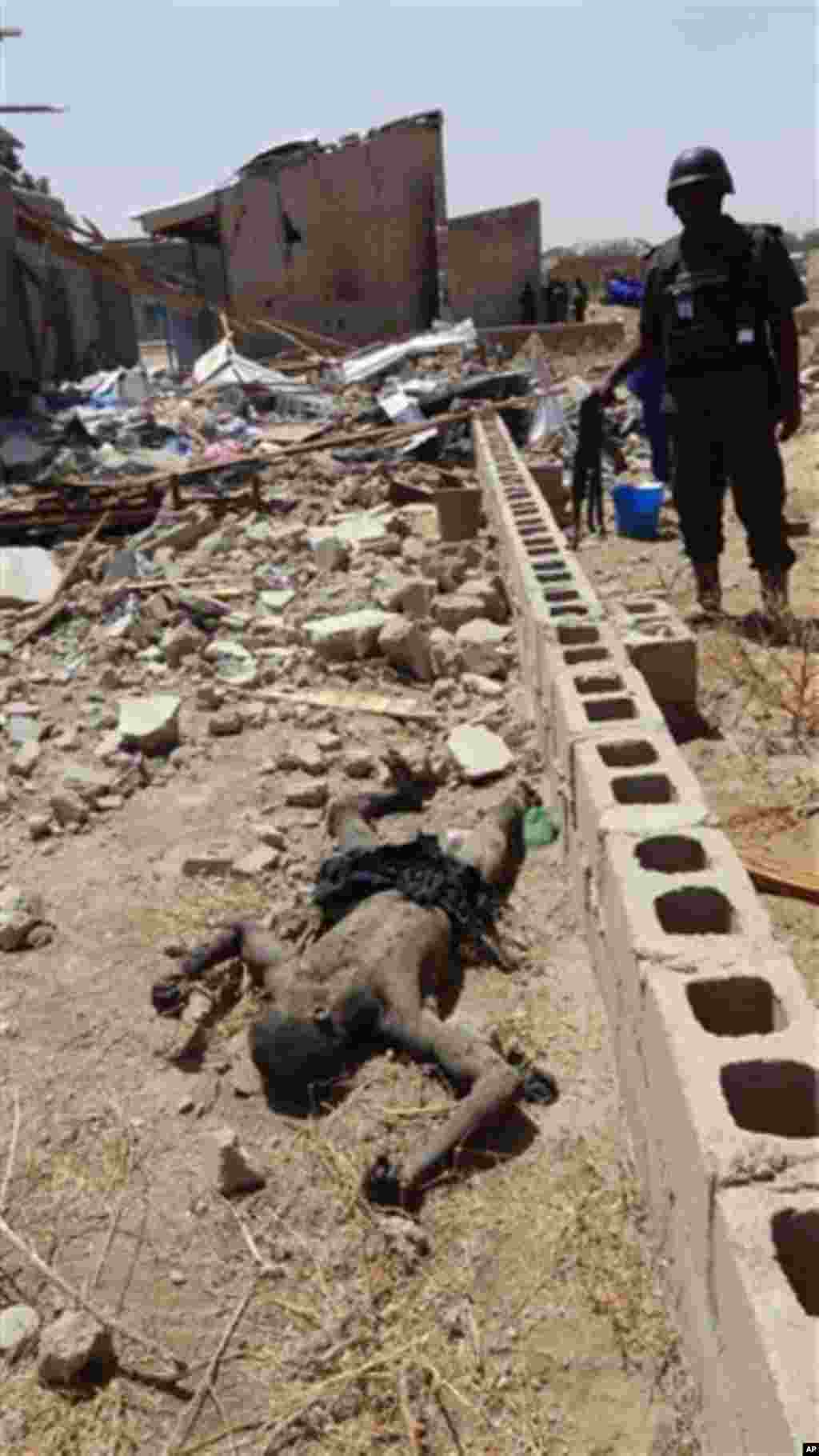 A police officer looks at the lifeless corpse of a suspected bomber thought to have been killed in a blast in a house in Maiduguri, Nigeria, on Friday, March 2, 2012.