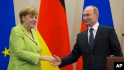 Presiden Rusia Vladimir Putin dan Kanselir Jerman Angela Merkel bersalaman setelah pembicaraan mereka di kediaman Putin di Sochi, Rusia.