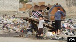 Neighbors collect trash from piles on the street in the hope that government trucks will soon remove the growing stacks of garbage from Mosul, Iraq, Jan. 9, 2017. (H. Murdock/VOA)