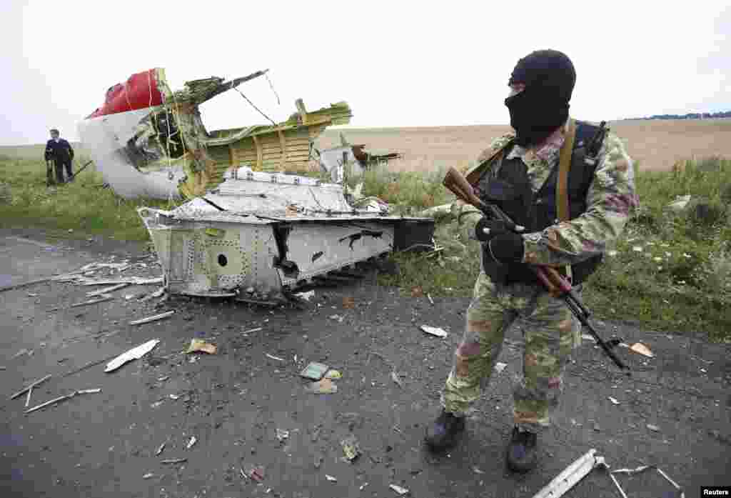 A pro-Russian separatist stands at the crash site of Malaysia Airlines flight MH17, near the settlement of Grabovo in the Donetsk region, July 18, 2014. 