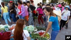 A Cambodian garment worker, foreground right, buys vegetable for her diner near a factory after the day's work, in Phnom Penh, file photo. 