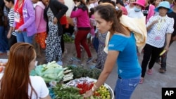 A Cambodian garment worker, foreground right, buys vegetable for her dinner near a factory after the day's work, in Phnom Penh, Cambodia, Wednesday, Nov. 12, 2014. (AP Photo/Heng Sinith)