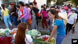 A Cambodian garment worker, foreground right, buys vegetable for her diner near a factory after the day's work, in Phnom Penh, file photo. 