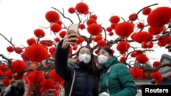 28일 음력 새해 첫 날을 맞아 베이징의 한 사원을 방문한 사람들이 휴대전화로 기념사진을 찍고 있다.