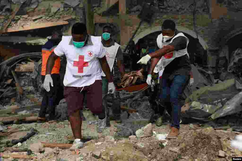 Paramedics carry a stretcher containing the body of a victim from one of the collapsed buildings at the scene of the pipeline explosion at Abule Ado in Lagos, Nigeria.