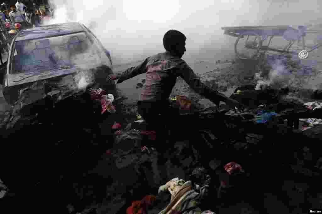 A boy tries to control a fire after vehicles were torched and vandalized by Jamaat-e-Islami party activists during clashes with police in Dhaka, Dec. 13, 2013. 
