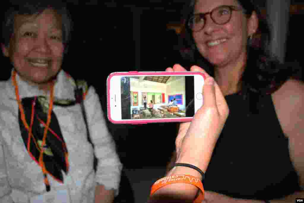 A guest shows photos of a partnering​ school of Caring for Cambodia at a Washington, DC fundraiser and silent auction organized by the non-profit to help support 21 impoverished schools in Cambodia&#39;s Siem Reap province, May 4, 2017. (VOA Khmer)&nbsp;