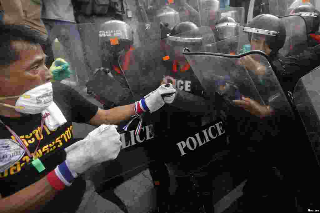 An anti-government protester fights with police at a barricade near Government House in Bangkok, Nov. 25, 2013.
