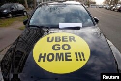 A striking French taxi drivers displays the message, "Uber Go Home" during a national protest about competition from private car ride firms like Uber, in Paris, Jan. 26, 2016.