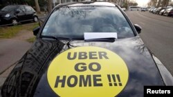 FILE - A striking French taxi drivers displays the message, "Uber Go Home" during a national protest about competition from private car ride firms like Uber, in Paris, Jan. 26, 2016. 