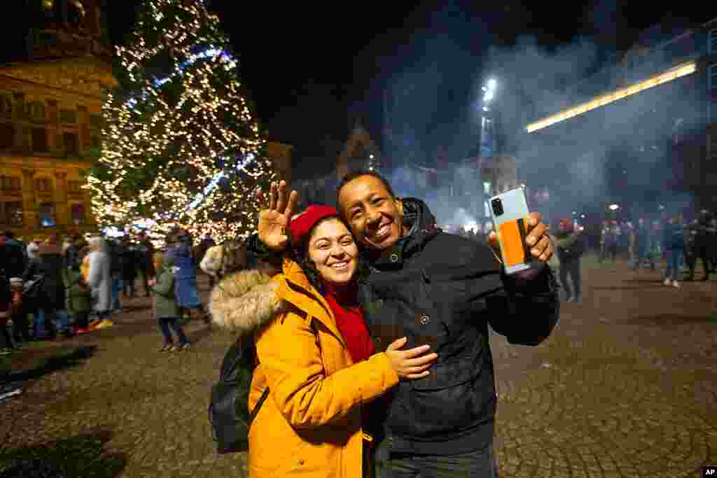 People celebrate New Year in front of the Royal Palace, rear left, in Amsterdam, Netherlands, Jan. 1, 2021. 