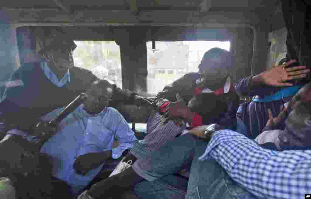 Protesters are beaten with wooden clubs inside the back of a police pickup truck after being arrested outside the Parliament building in Nairobi, Kenya Thursday, Dec. 18, 2014.