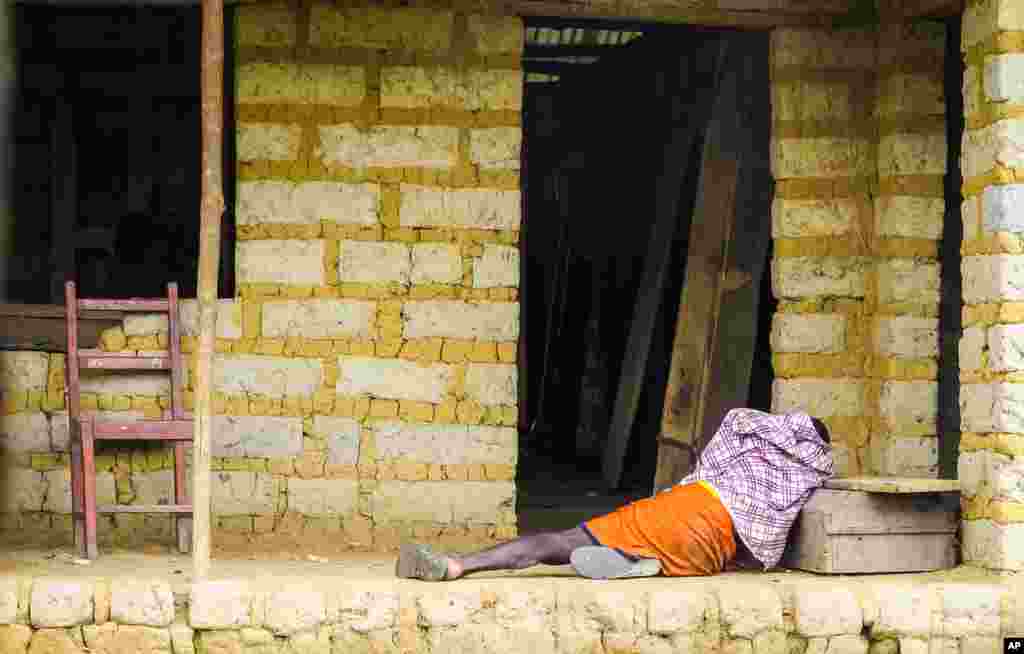 A man suffering from the Ebola virus lies on the floor outside a house in Port Loko Community, on the outskirts of Freetown, Sierra Leone.