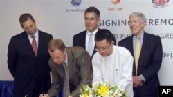 President and CEO of General Electric ASEAN, Stuart Dean, second from left, signs documents during the signing ceremony between Sea Lion Co. Ltd., General Electric Healthcare and Bahosi and Pun Hlaing Hospitals in Yangon, Myanmar, Saturday, July. 14, 2012