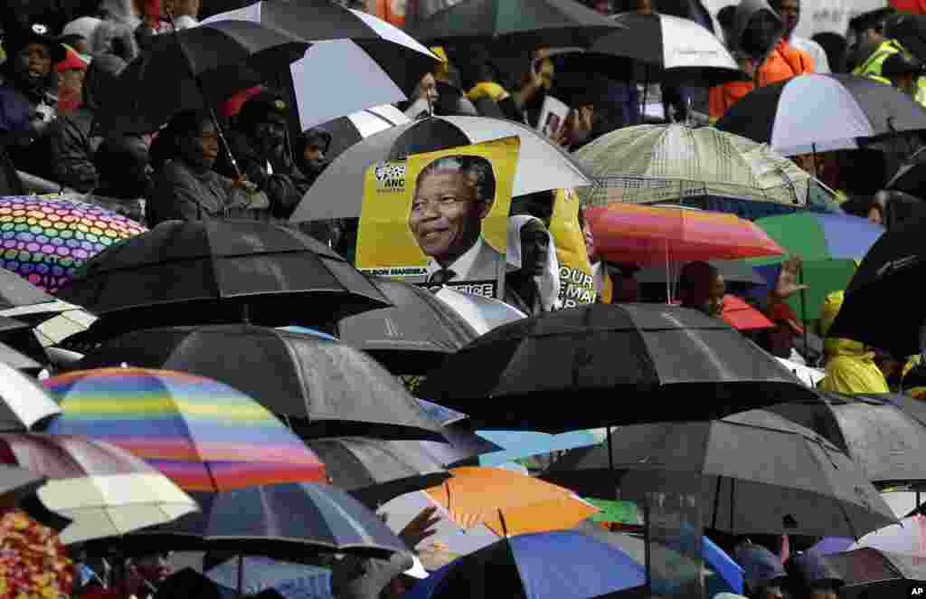 O retrato de Mandela ao fundo, no meio de guarda-chuvas, durante a cerimónia fúnebre oficial no Estádio FBN, no Soweto, junto a Joanesburgo, Dez. 10, 2013.