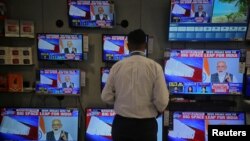 A salesman watches Prime Minister Narendra Modi addressing to the nation, on TV screens inside a showroom in Mumbai, India, March 27, 2019. 