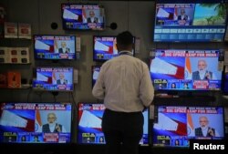 FILE - A salesman watches Prime Minister Narendra Modi addressing to the nation, on TV screens inside a showroom in Mumbai, India, March 27, 2019.